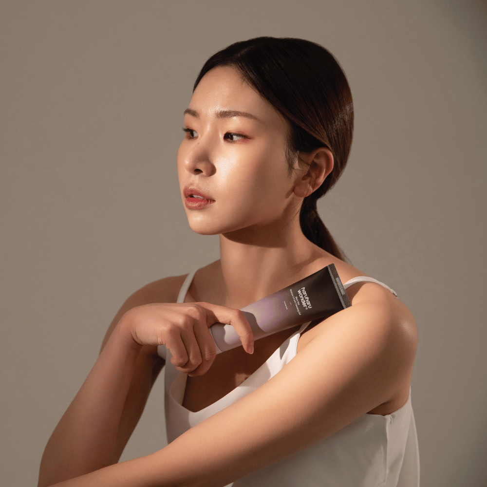 Nuori aasialainen nainen, joka pitää harjaa kädessään käyttäessään Haruharu Wonders Black Rice Moisture 5.5 Soft Cleansing Gel 100ml.