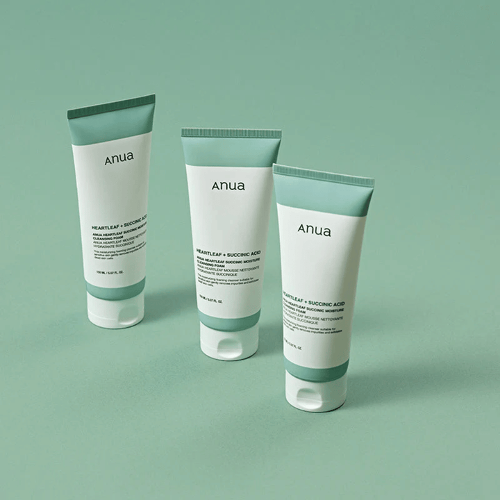 Kolme pakkausta Anua Heartleaf + Succinic Acid Moisture Cleansing Foam -tuotetta esiteltynä vaaleanvihreää taustaa vasten. Kuva korostaa tuotteen puhdasta ja minimalistista muotoilua sekä antaa ammattimaisen vaikutelman tuotesarjasta.