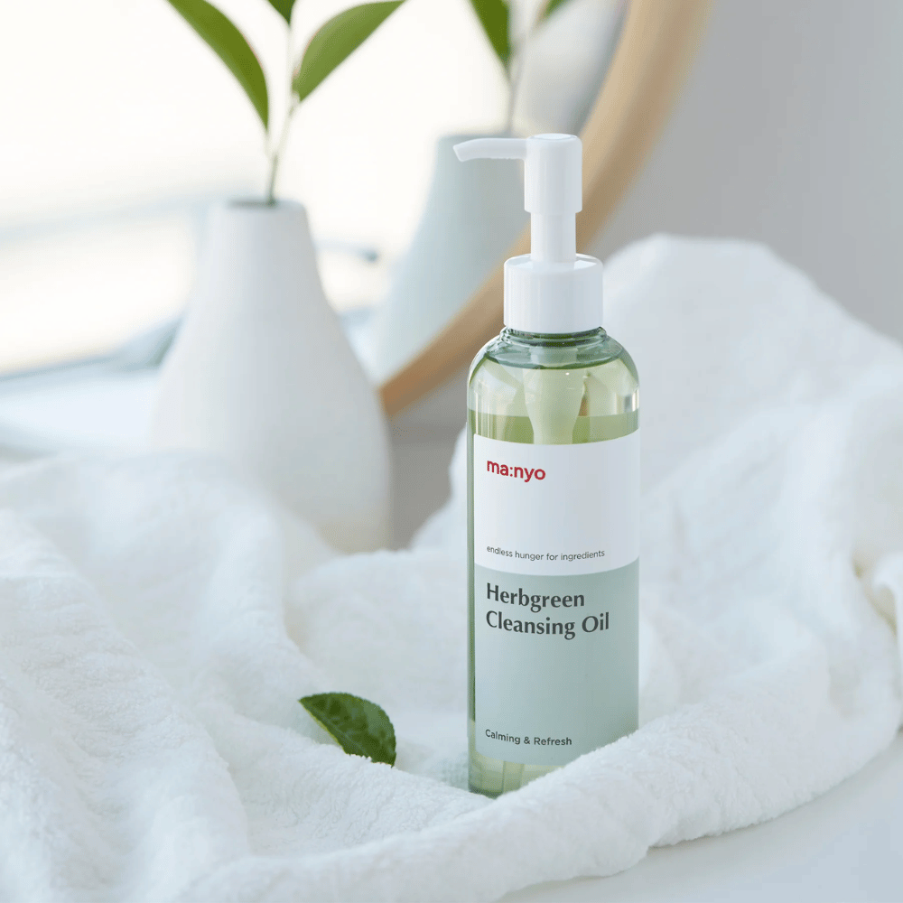 ma:nyo Herbgreen Cleansing Oil pumppupullossa valkoisella pyyhkeellä, rauhoittava puhdistusöljy yrttipohjaisilla ainesosilla hellävaraiseen kasvojen puhdistukseen