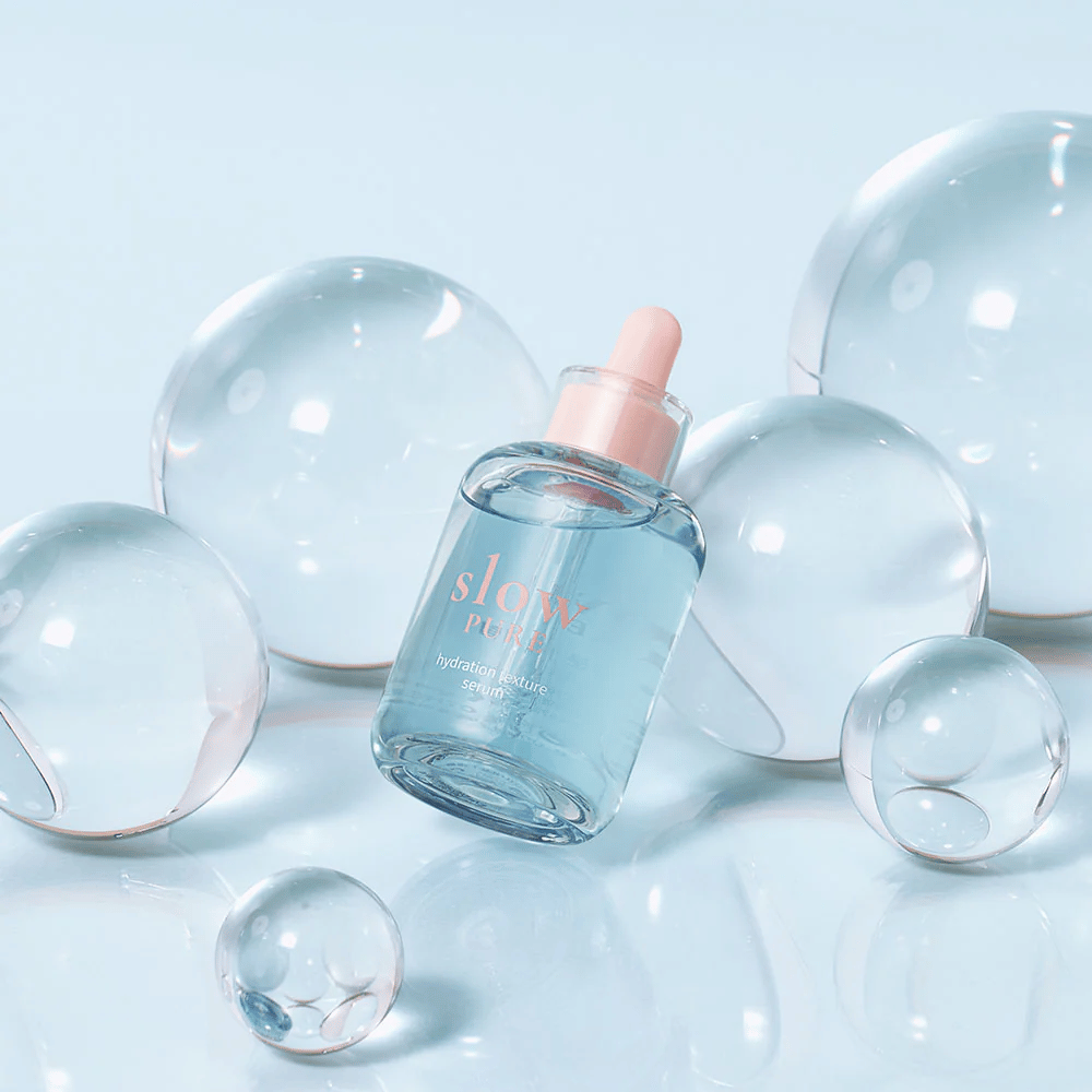 Slow Pure Hydration Texture Serum sijoitettuna läpinäkyvien kuplien keskelle, symboli intensiiviselle kosteutukselle.