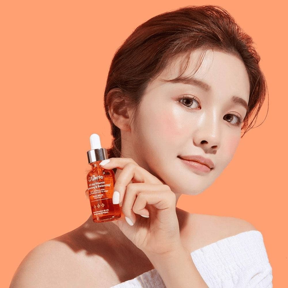 Nainen, joka pitelee pulloa JUMISO All Day Vitamin Brightening & Balancing Facial Serum 30ml.