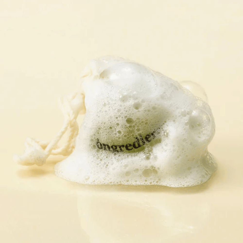Óngredients Jeju Green Tea Cleansing Ball verkkopussissa pehmeän vaahdon peittämänä – luonnollinen korealainen kasvosaippua.