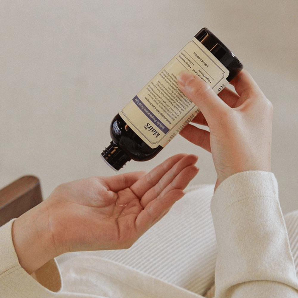 Henkilö pitää pulloa Klairs Supple Preparation Facial Toner ylösalaisin kädessään, valmiina annostelemaan tuotetta.