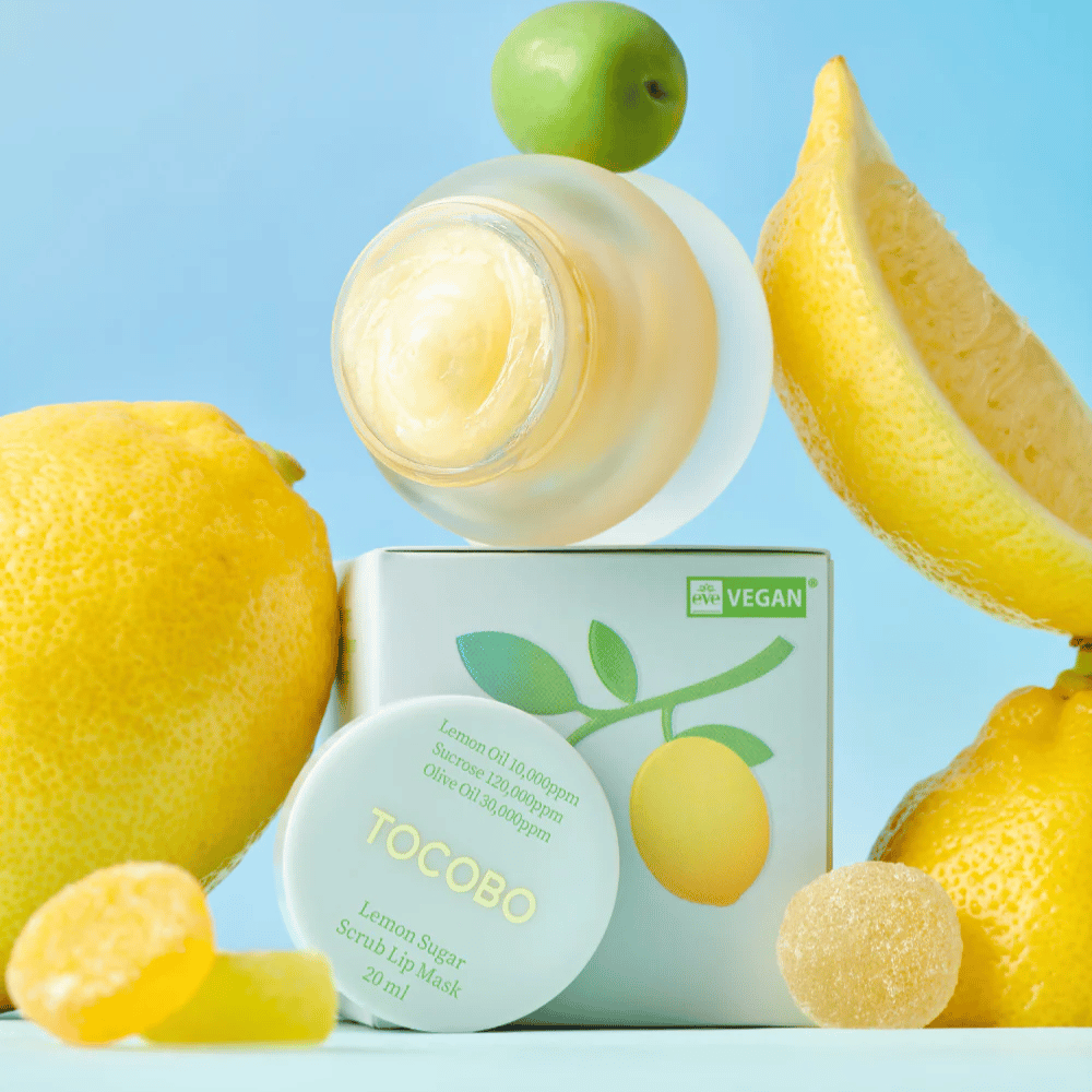 Purkki Tocobo Lemon Sugar Scrub Lip Mask sijoitettuna sitruunoiden ja pakkauksen joukkoon, merkitty vegaaniystävälliseksi.