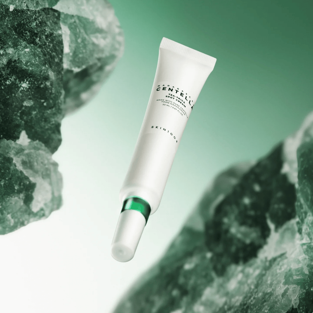 SKIN1004 Madagascar Centella Tea-Trica Spot Cream 20 ml aknea ja näppyjä vastaan, tuotekuva vihreällä taustalla ja kristallirakenteella – rauhoittava täsmähoito centella asiaticalla ja tea tree.
