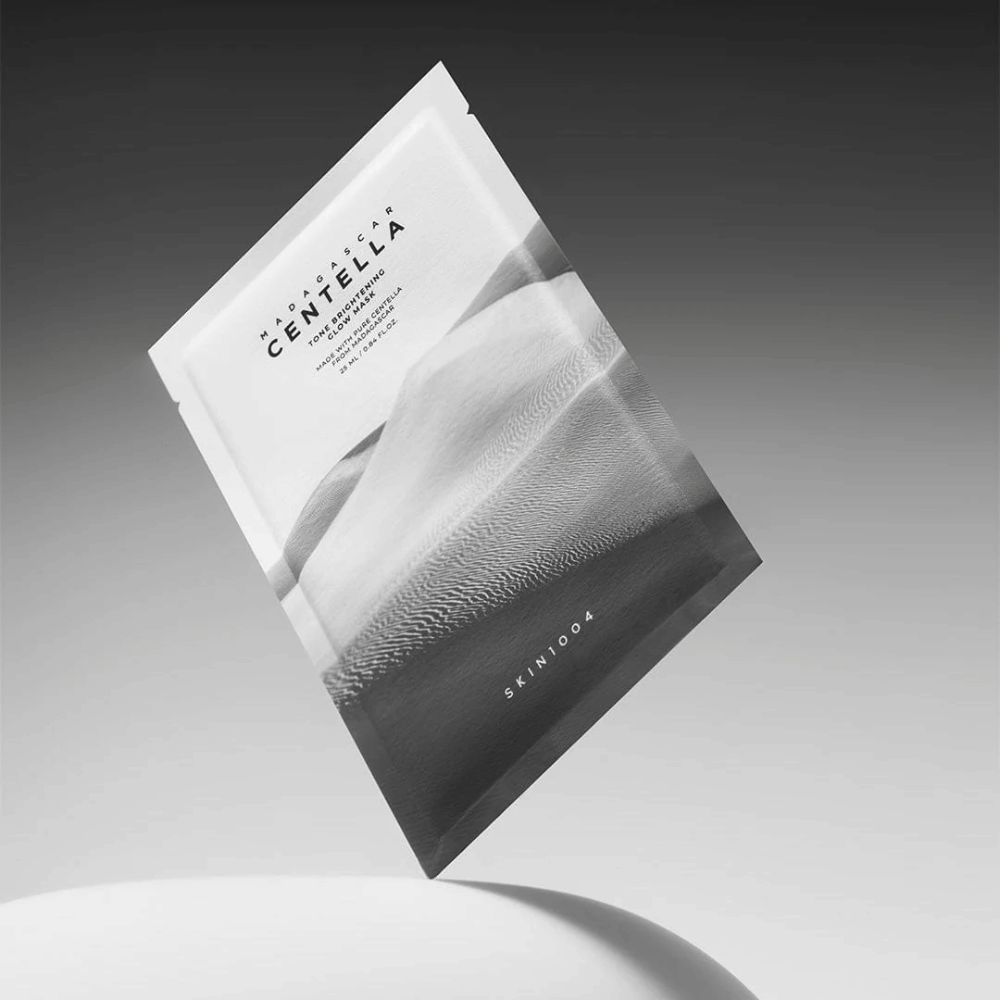 Sheet mask-pakkaus merkiltä SKIN1004 leijumassa harmaata taustaa vasten minimalistisella muotoilulla.