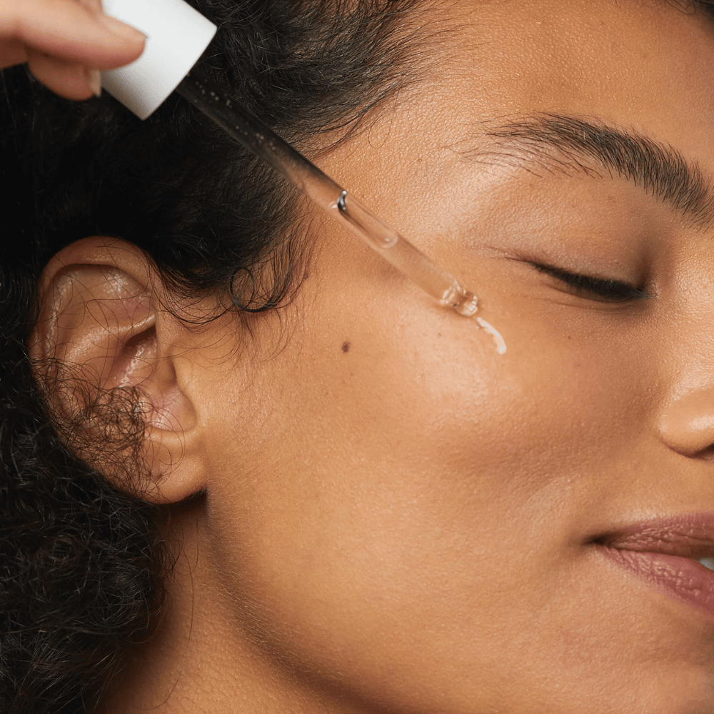 Nainen levittää Skin1004 Madagascar Centella Hyalu-Cica First Ampoule poskelle pipetillä.