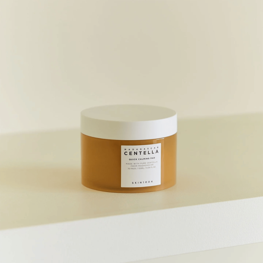 SKIN1004 Madagascar Centella Quick Calming Pad sijoitettu valkoiselle hyllylle – meripihkanvärinen purkki, jossa on valkoinen kansi ja selkeä etiketti edessä.