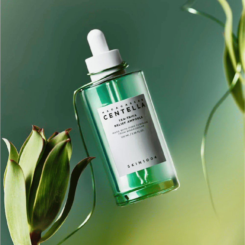 SKIN1004 Madagascar Centella Tea-Trica Relief Ampoule – vihreä lasipullo, jossa on pipetti, valkoinen etiketti ja 100 ml sisältöä, kuvattu vihreää taustaa vasten kasvien yksityiskohdilla.