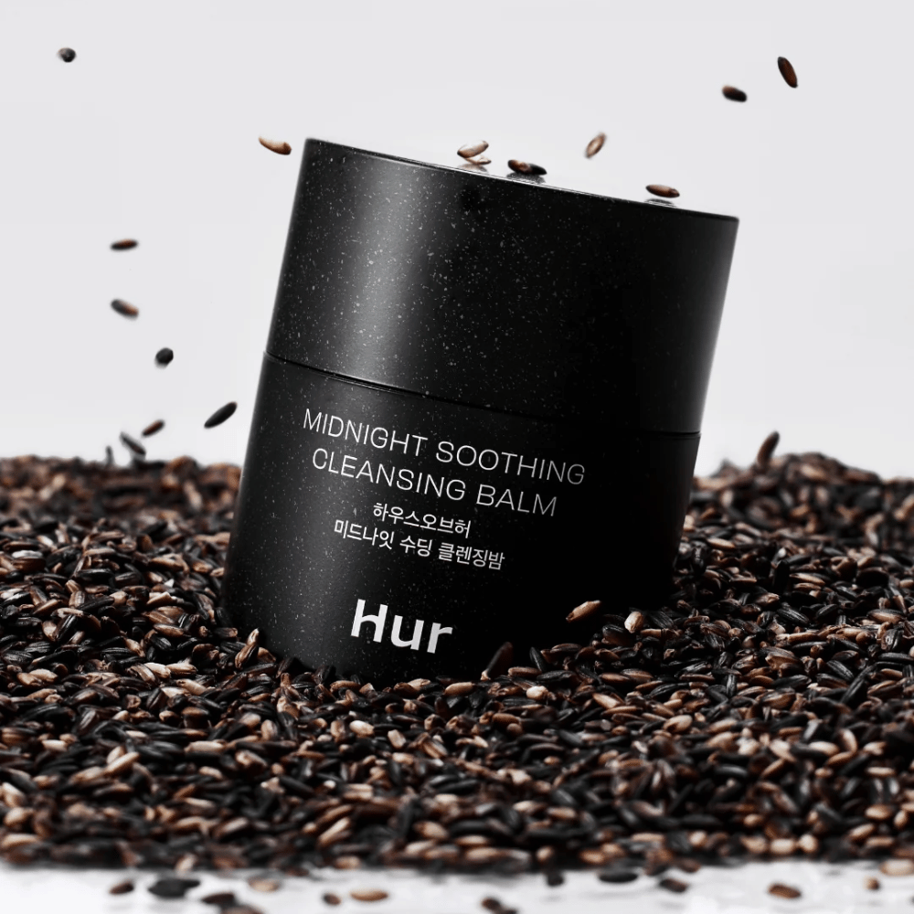 Miten Midnight Soothing Cleansing Balm mustassa purkissa mustien siementen päällä. Rauhoittava puhdistusbalmi, joka liuottaa meikin ja epäpuhtaudet samalla kun iho hoidetaan.