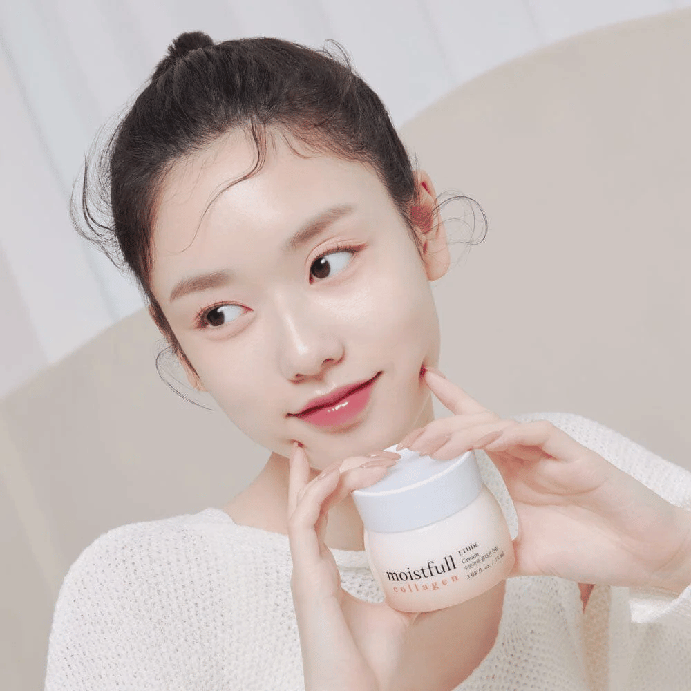 Nainen pitää purkkia "Moistfull Collagen Cream", valkoinen paita, hymyilee.