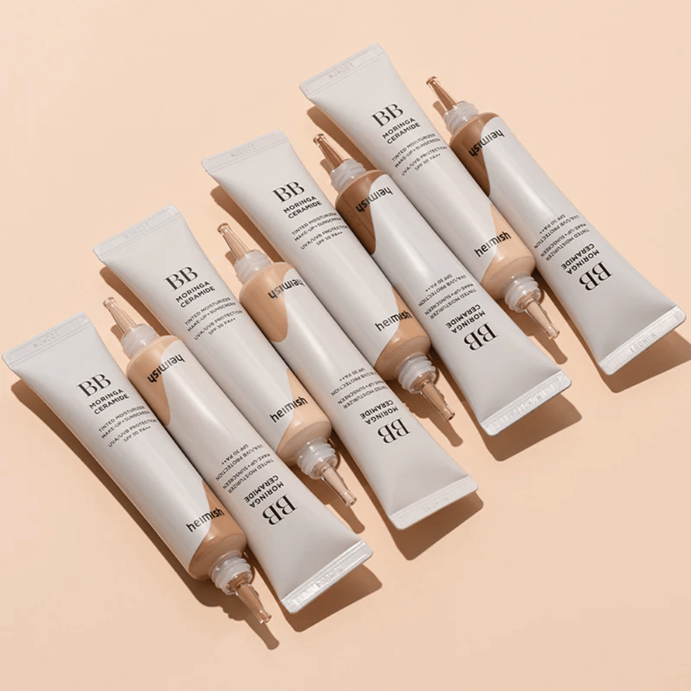 Useita tuubeja tuotteesta Heimish Moringa Ceramide BB Cream aseteltuna vaaleanbeigelle taustalle. Kuva tuo esiin eri sävyt ja tuotteen elegantin, minimalistisen pakkaussuunnittelun.