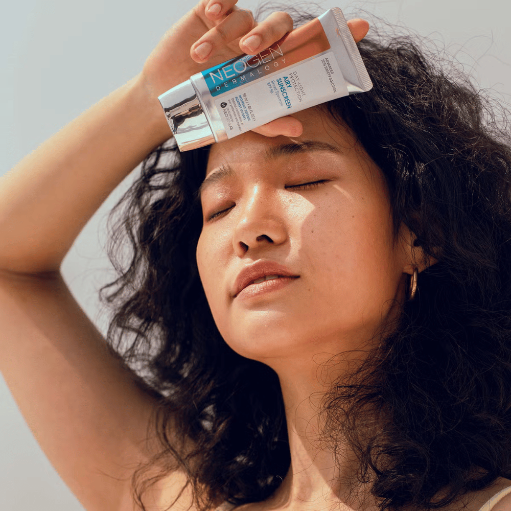Neogen Dermalogy Day-Light Protection Airy Sunscreen SPF50 50ml – kevyt aurinkovoide, jossa on laajakirjoinen UV-suoja, näytetty käytössä auringonvalossa.