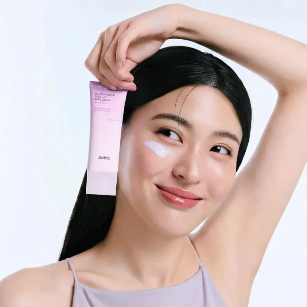 Malli pitelee tuotetta JUMISO Niacinamide 3+ Tone-Up Sunscreen SPF50+ PA++++ – aurinkovoide niasiiniamidilla, joka tasoittaa ihonsävyä ja suojaa ihoa.