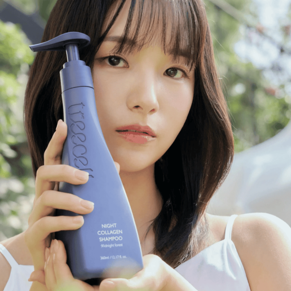 Nainen pitelee tuotetta Treecell Night Collagen Shampoo Midnight Forest luonnollisessa ympäristössä. Kuva välittää terveitä hiuksia, kiiltoa ja premium-tuntua keskittyen hiusten ja hiuspohjan hoitoon.