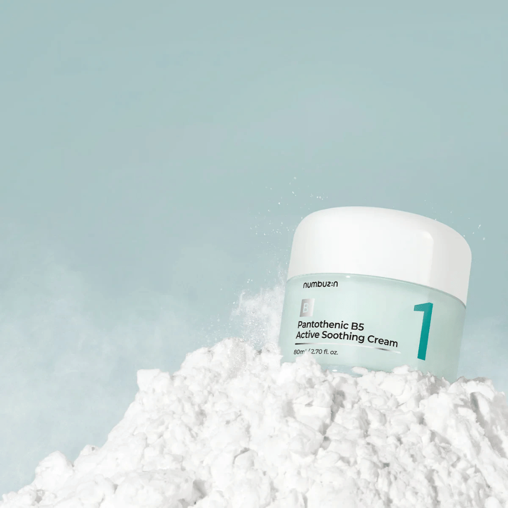 Numbuzin No.1 Pantothenic B5 Active Soothing Cream 80 ml vaaleanvihreässä purkissa, jossa on valkoinen kansi, sijoitettuna valkoisen jauheen kasalle vaaleaa taustaa vasten.