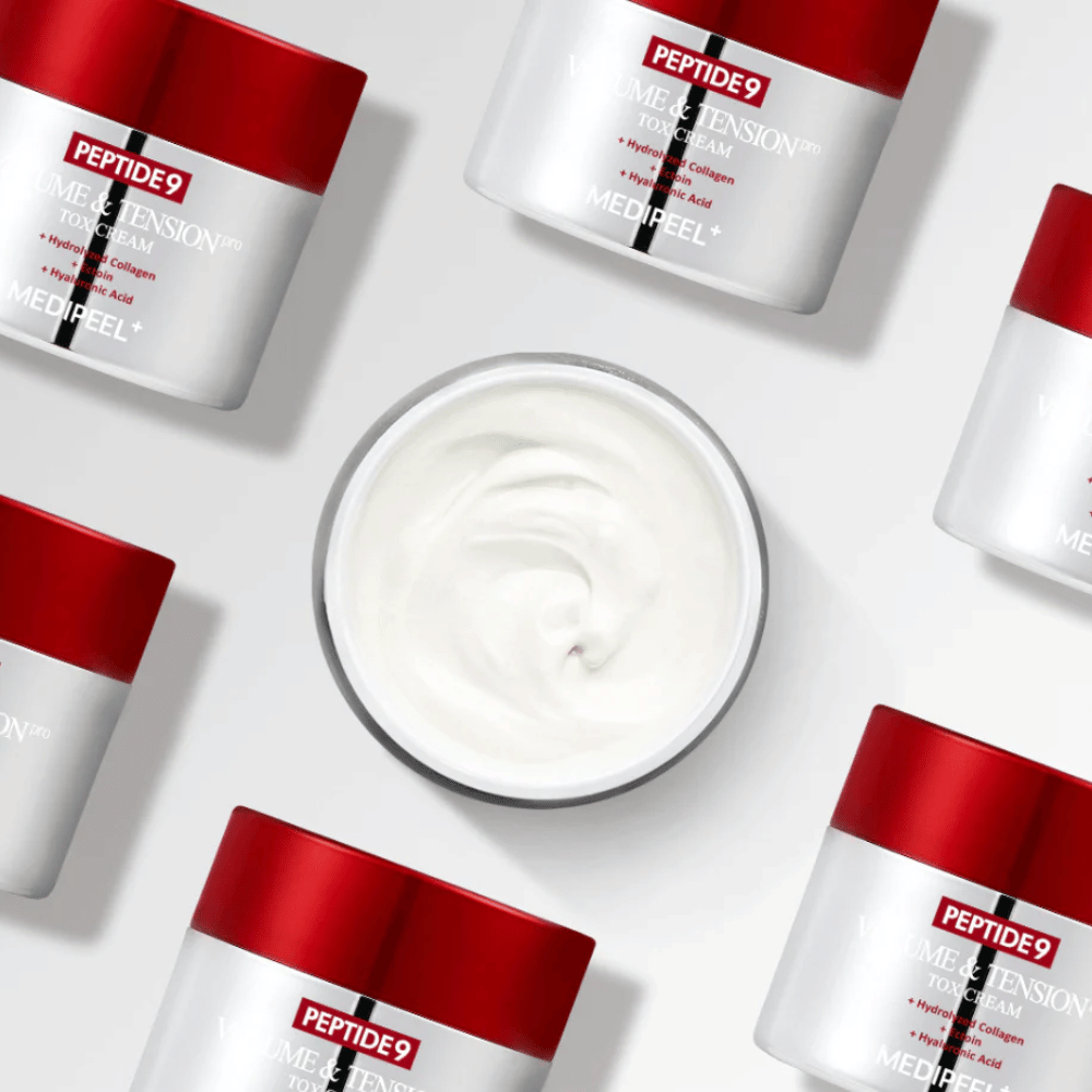 Useita purkkeja MEDI-PEEL Peptide 9 Volume & Tension Tox Cream -voidetta aseteltuna valkoista taustaa vasten. Tuote kosteuttaa intensiivisesti ja antaa iholle volyymia ja hehkua.
