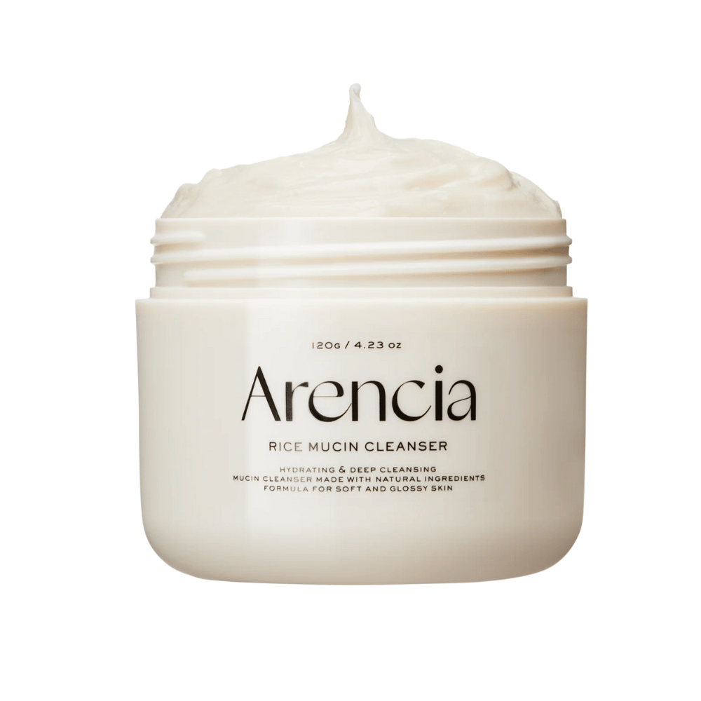 Tuotekuva Arencia Rice Mucin Cleanser valkoisessa purkissa, josta nousee kermainen, vatkattu koostumus. Pakkauksen teksti korostaa kosteutusta ja syväpuhdistusta.