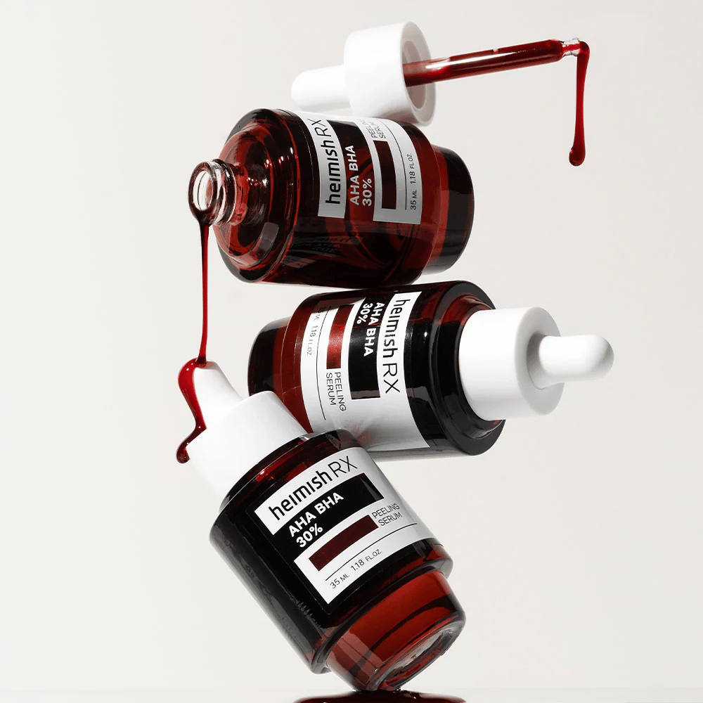 Kolme pulloa Heimish RX AHA BHA 30% Peeling Serum -seerumia dynaamisessa sommitelmassa, jossa punainen seerumi tippuu pipeteistä.