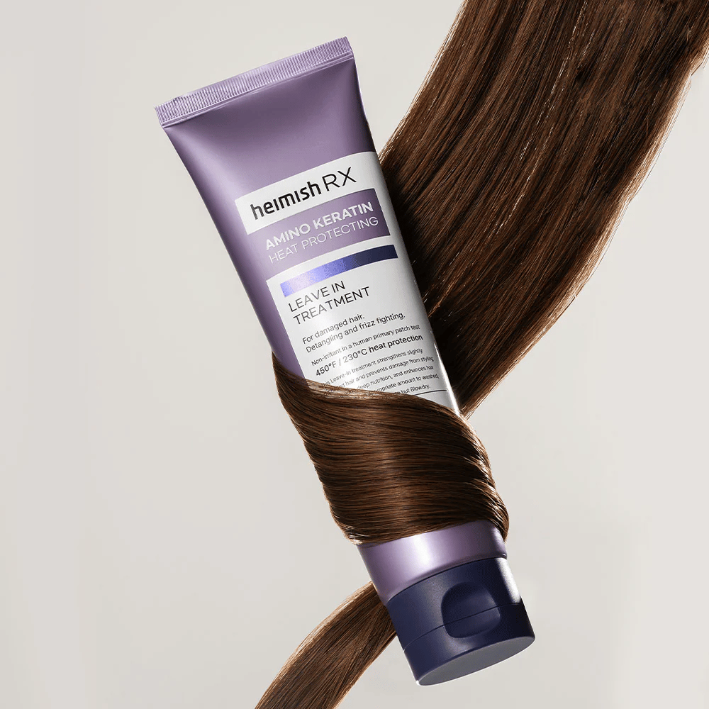 Heimish RX Amino Keratin Leave-In Treatment -ravitseva lämpösuojaava hiustenhoito kiiltävien hiusten ympäröimänä, symboloi vahvistavaa ja kosteuttavaa vaikutusta vaurioituneille hiuksille.