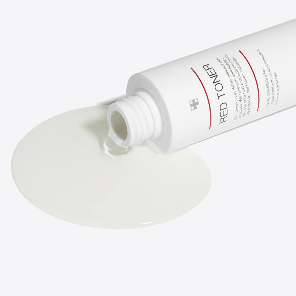 Avoin pullo medicube Red Toner, joka kaadetaan valkoiselle pinnalle – näyttää tuotteen kevyen ja nestemäisen koostumuksen.