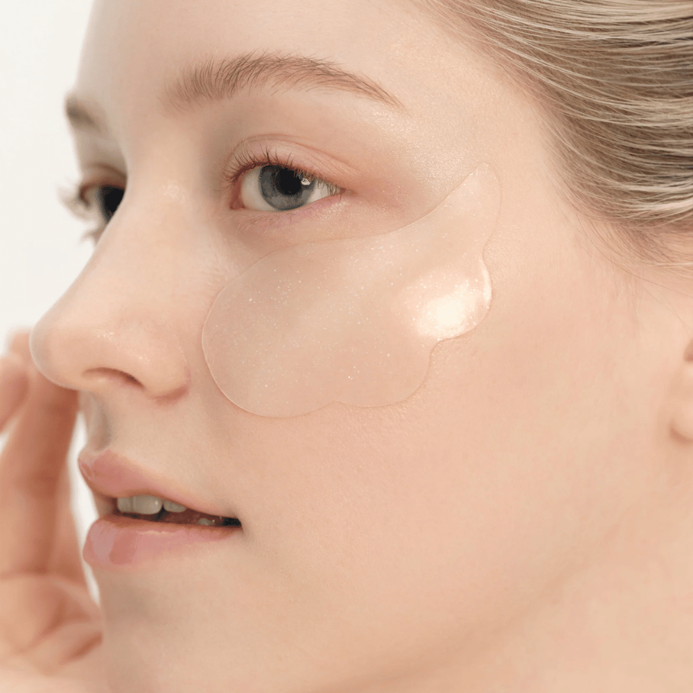 Lähikuva mallista, joka levittää Beauty of Joseon silmänympäryslappua silmän alle kosteutuksen, hehkun ja kiinteyttävän vaikutuksen saamiseksi.