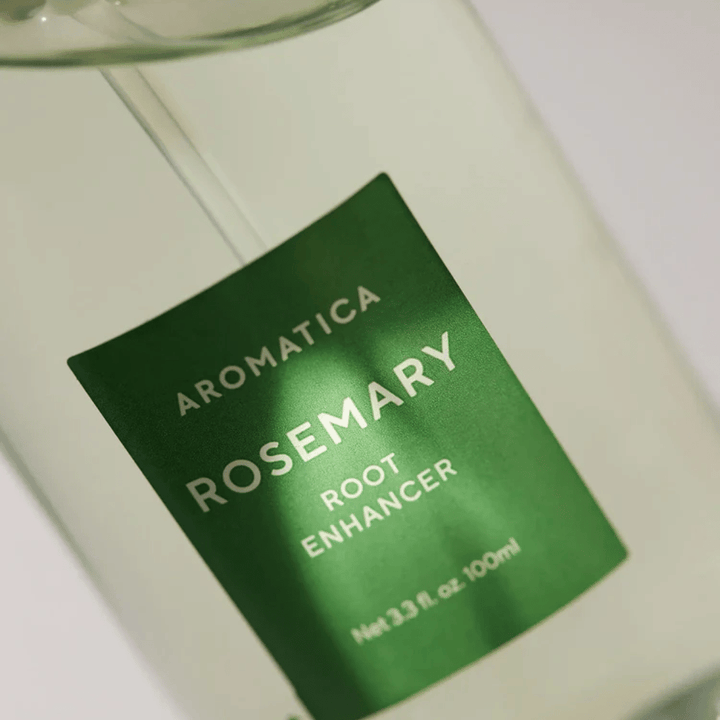 Yksityiskohtainen kuva AROMATICA Rosemary Root Enhancer -tuotteen etiketistä. Vihreä etiketti ja läpinäkyvä pullo korostavat tuotteen puhdasta ja minimalistista ulkonäköä.