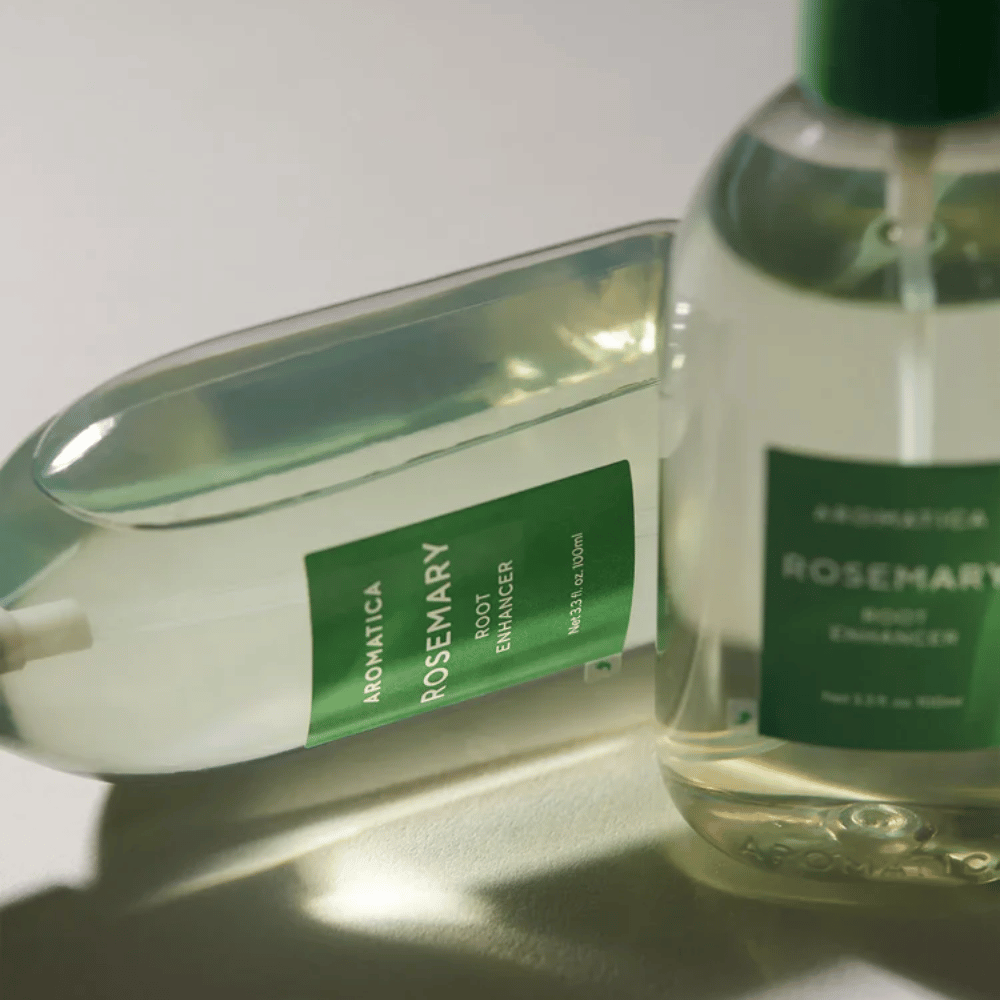 Kaksi AROMATICA Rosemary Root Enhancer -pulloa läpinäkyvällä suojakorkilla ja vihreällä etiketillä. Lähikuva, joka korostaa tuotteen premium-muotoilua ja luonnollisen hiustenhoidon konseptia.