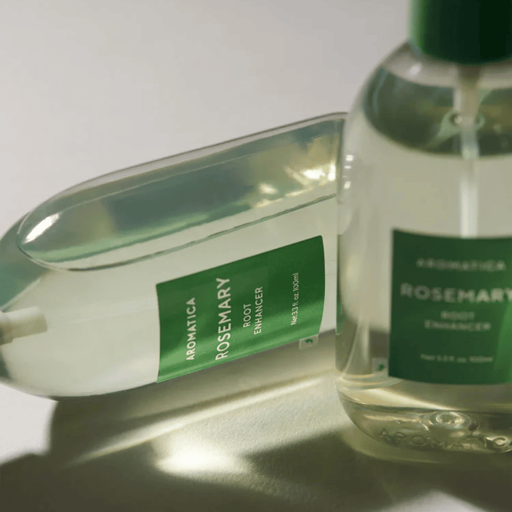 Kaksi AROMATICA Rosemary Root Enhancer -pulloa läpinäkyvällä suojakorkilla ja vihreällä etiketillä. Lähikuva, joka korostaa tuotteen premium-muotoilua ja luonnollisen hiustenhoidon konseptia.