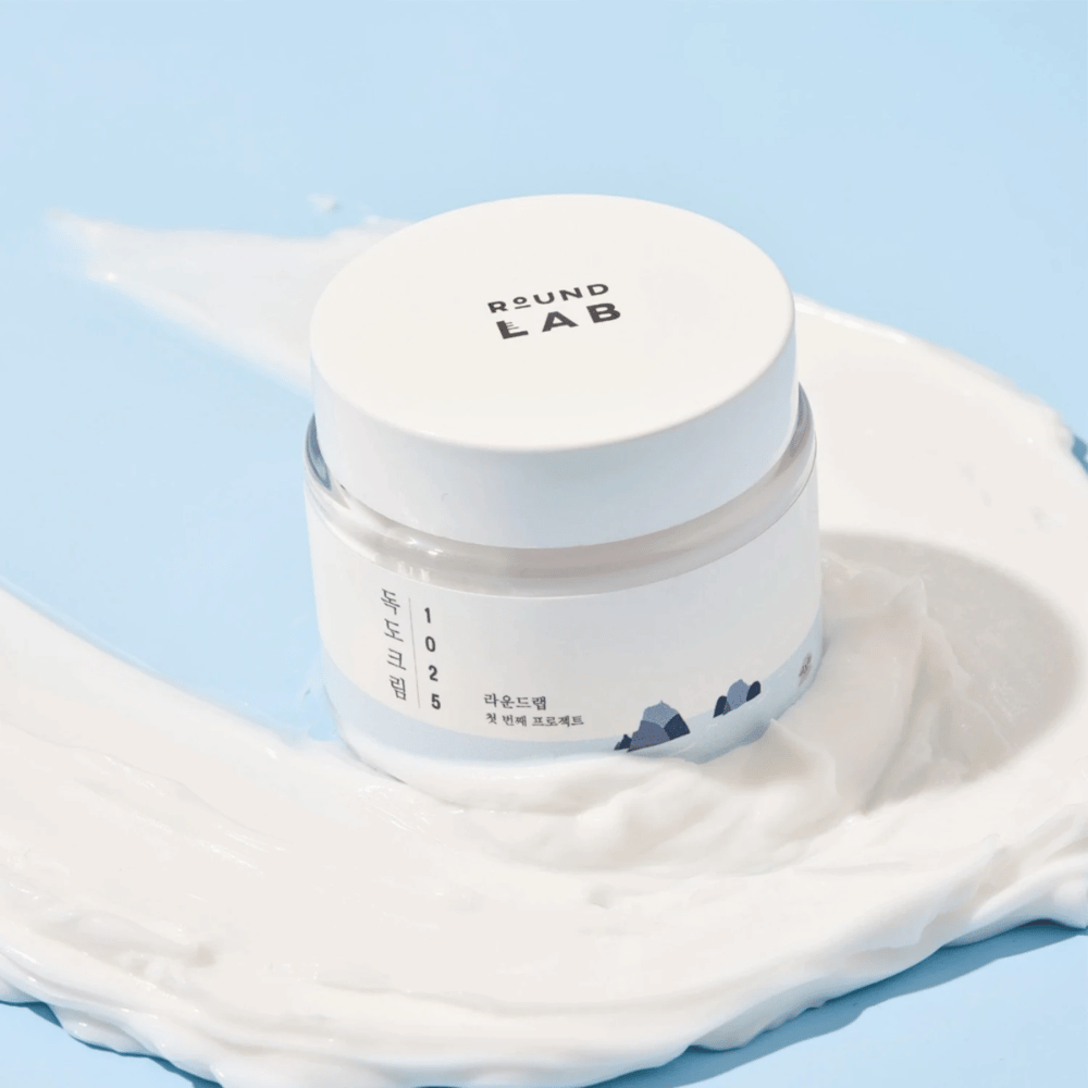 Purkillinen Round Labs 1025 Dokdo Cream 80 ml kosteutusta varten, sijoitettuna eloisalle siniselle taustalle.