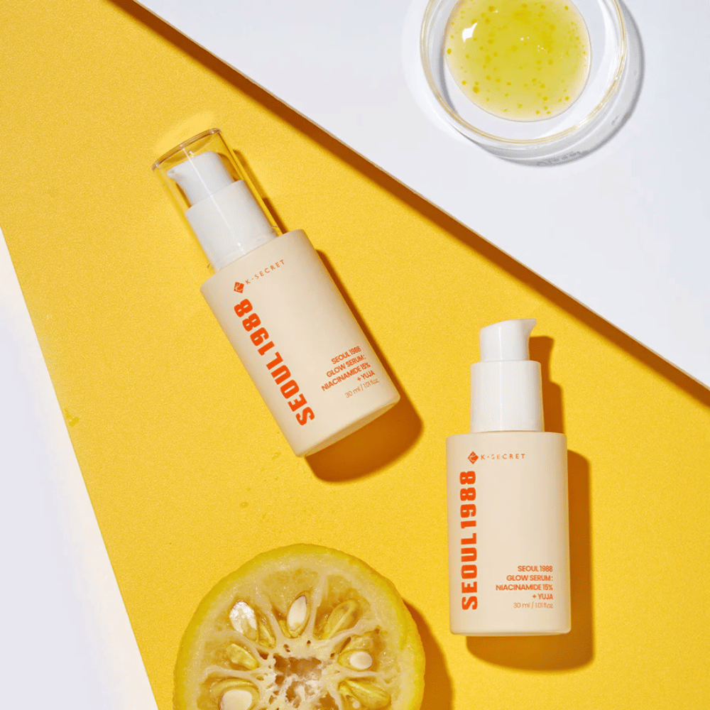 Kaksi pulloa Seoul 1988 Glow Serum sijoitettuna keltaiselle taustalle yhdessä kulhon keltaisen seerumin ja puolikkaan sitrushedelmän kanssa.