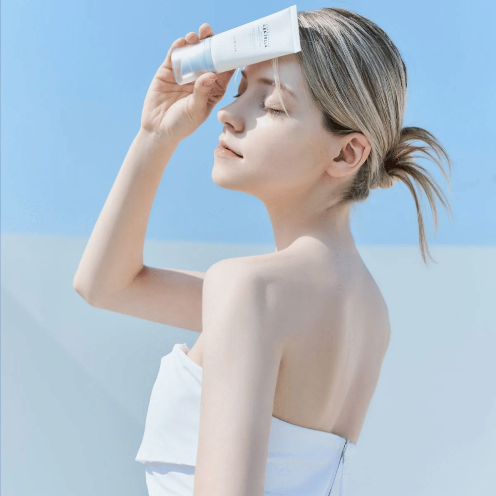 Eräs nainen levittää SKIN1004 Madagascar Centella Hyalu-Cica Water-Fit Sun Serum 50ml suojatakseen kasvonsa UV-säteiltä.