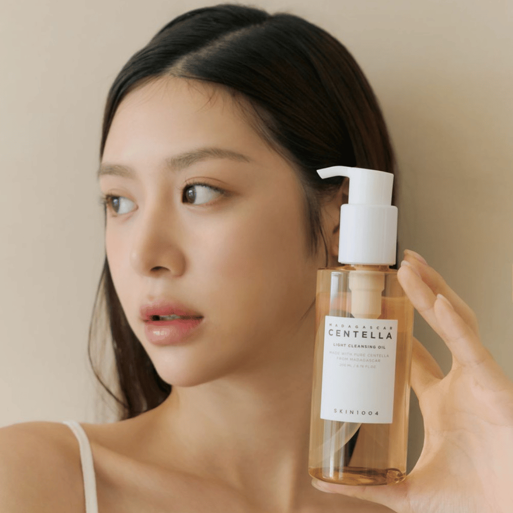 Nainen, joka pitää ylös pullon SKIN1004 Madagascar Centella Light Cleansing Oil 200 ml kasvopuhdistusainetta.