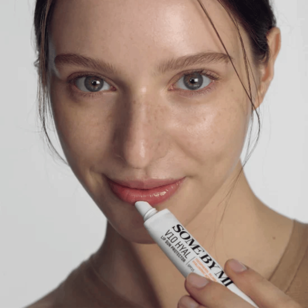 Nainen pitää kädessään putkiloa V10 Hyal Lip Sun Protector SPF15 7ml aurinkosuojalla ja kosteutuksella varustettua huulirasvaa, valmistaja SOME BY MI.