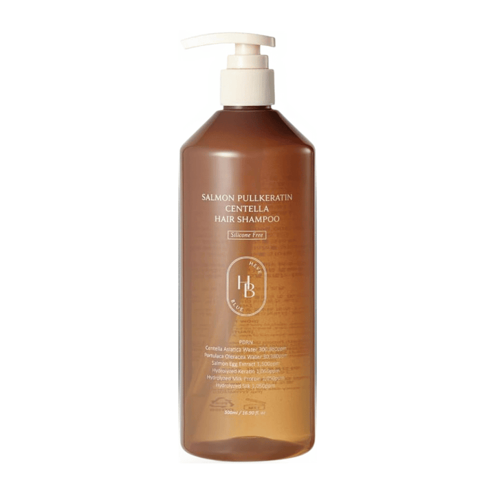 Heveblue Salmon Pullkeratin Centella Hair Shampoo läpinäkyvän ruskeassa pumppupullossa vaaleaa taustaa vasten. Shampoo, jossa on centellaa, lohiuutetta ja keratiinia ja joka auttaa puhdistamaan ja hoitamaan hiuksia.