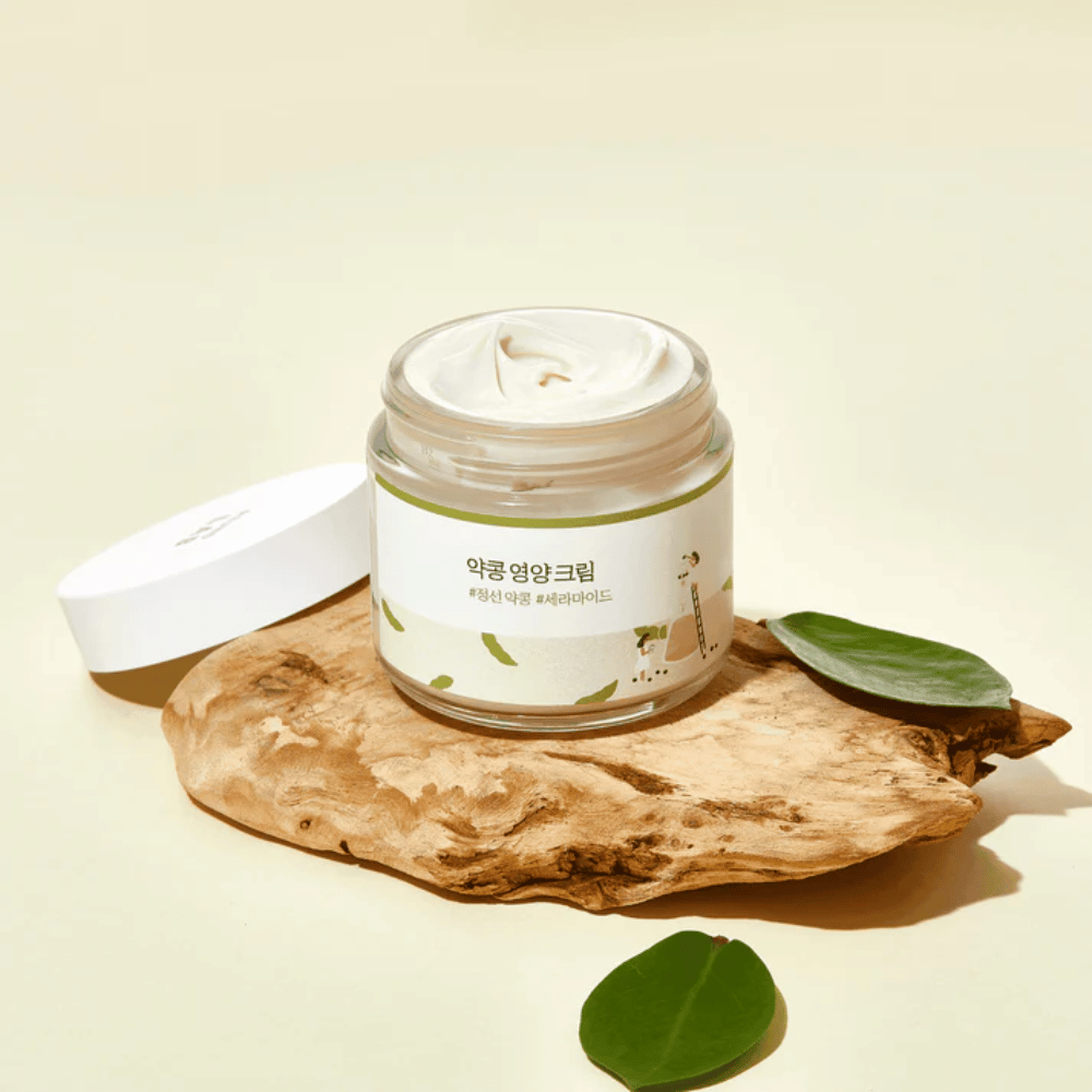 Mixsoon Soybean Nourishing Cream avoimessa purkissa puukappaleella vihreiden lehtien kanssa. Ravitseva voide fermentoiduilla soijapavuilla ja keramideilla.