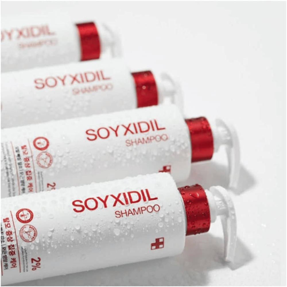 Useita pulloja Medicube Soyxidil Shampoo rivissä vesipisaroiden kanssa – osoittaa tuotteen raikkaan ja hoitavan tunteen.