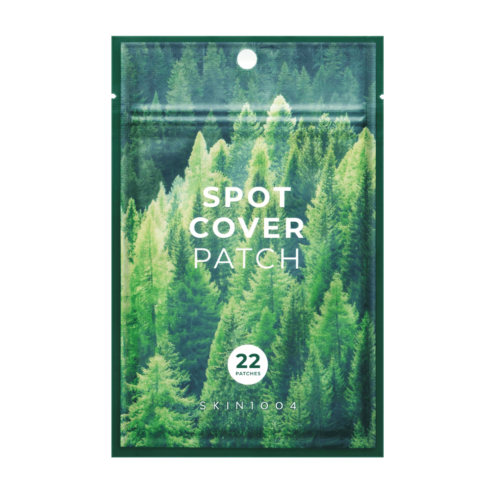 Pakkaus, jossa on "Spot Cover Patch" ja joka sisältää 22 laastaria, suunniteltu vihreällä metsäkuviolla. Teksti "SPOT COVER PATCH" on painettu valkoisella etupuolelle, ja ympyrä merkitsee laastareiden määrän. Tuote on merkiltä SKIN1004.