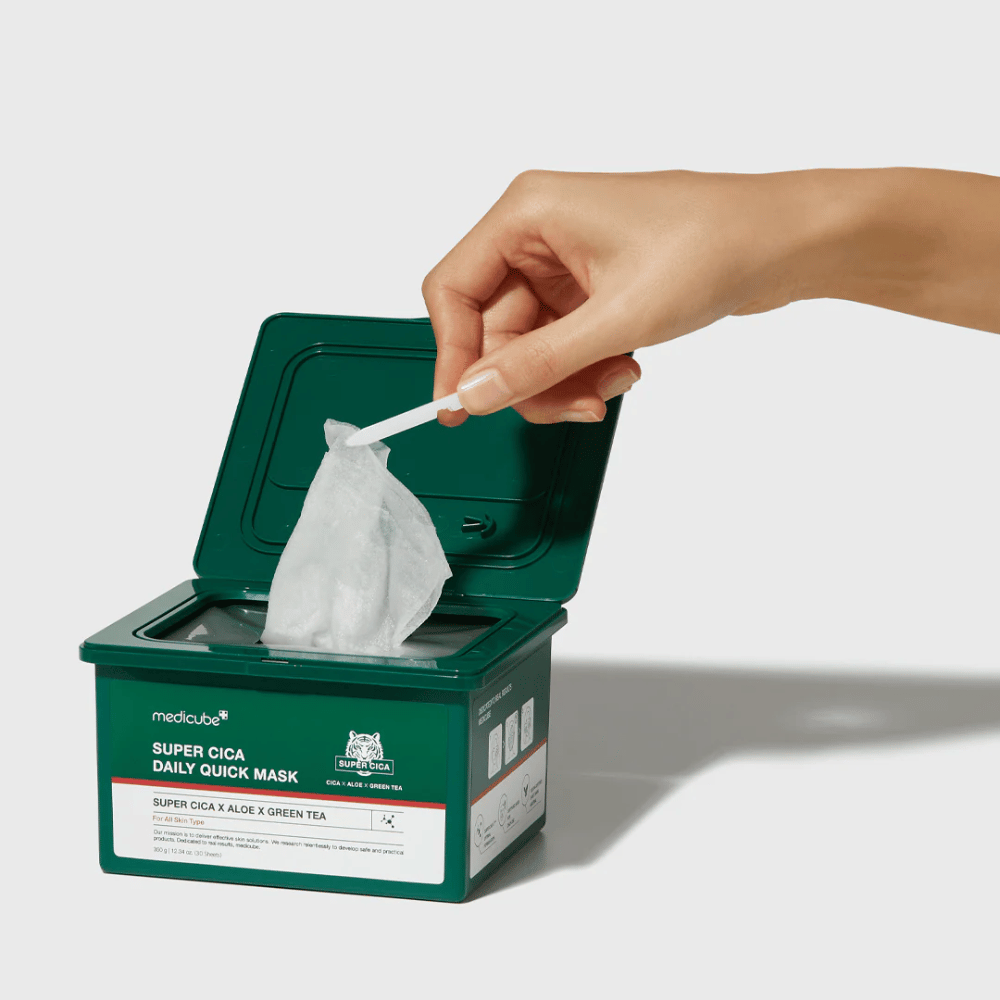 Vihreä säiliö, jossa on avoin kansi, näyttää medicube Super Cica Daily Quick Mask. Käsi nostaa arkkinaamion mukana tulevilla pinseteillä. Tuote sisältää Cicaa, aloe veraa ja vihreää teetä, ihanteellinen nopeaan kosteutukseen ja rauhoittavaan vaikutukseen.