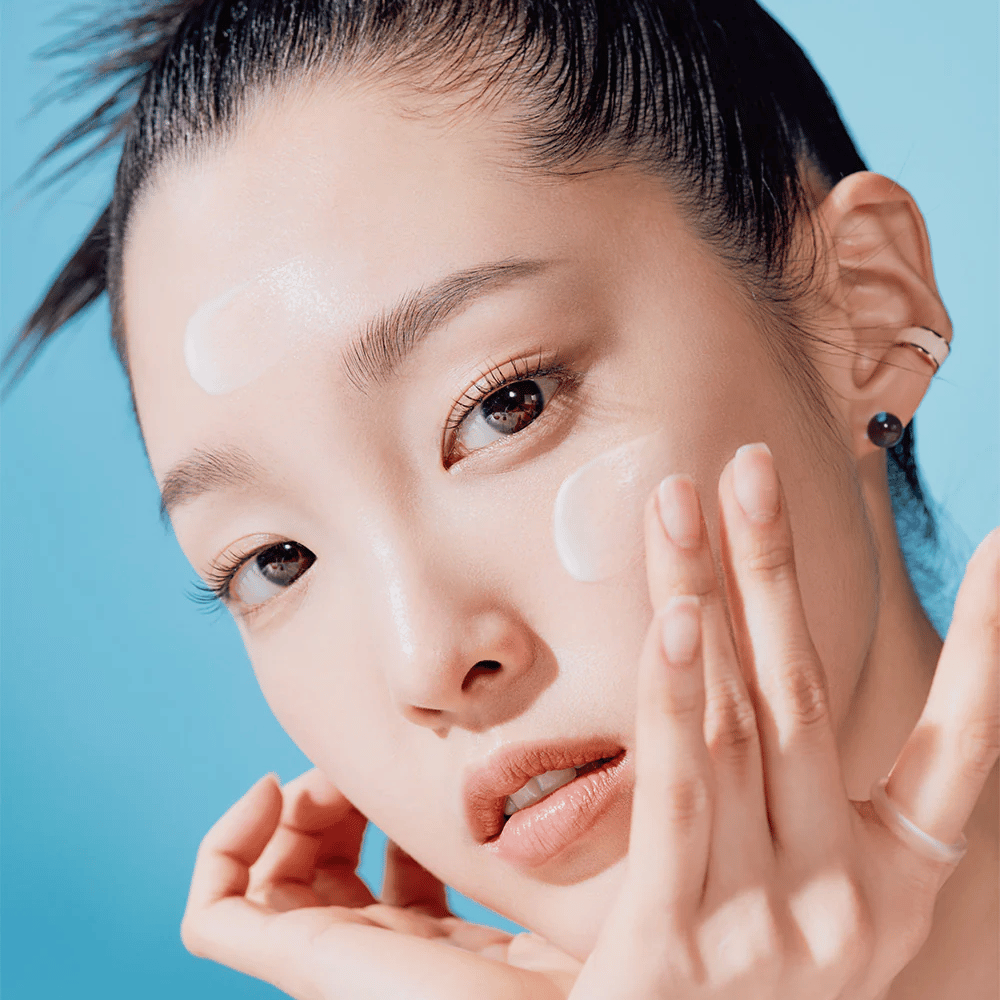 Nainen poseeraa kädet kasvoillaan TOCOBO Bio Watery Sun Cream SPF50+ PA++++ 50ml luonnollisen ihonhoitokampanjan yhteydessä.
