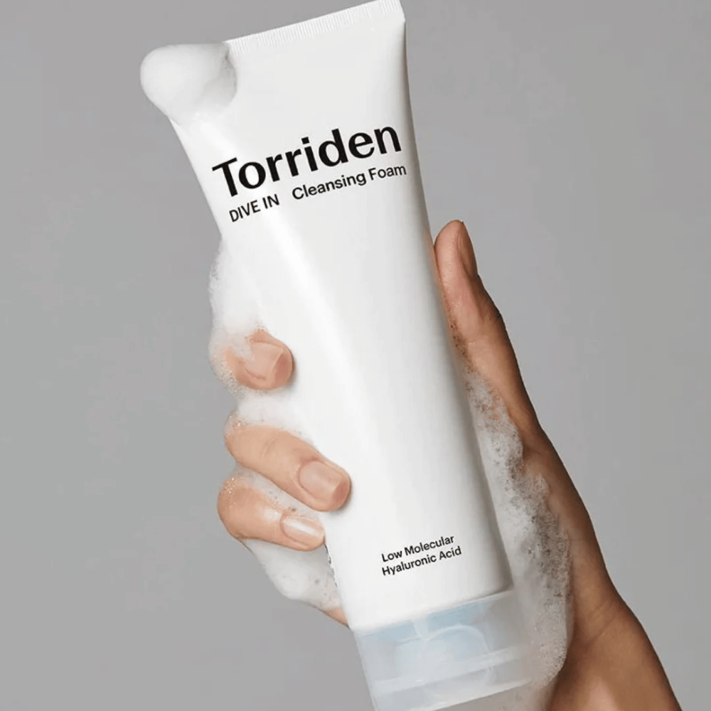 Käsi, joka pitää pH-tasapainotettua tuubia Torriden DIVE-IN Low Molecular Hyaluronic Acid Cleansing Foam 150 ml.
