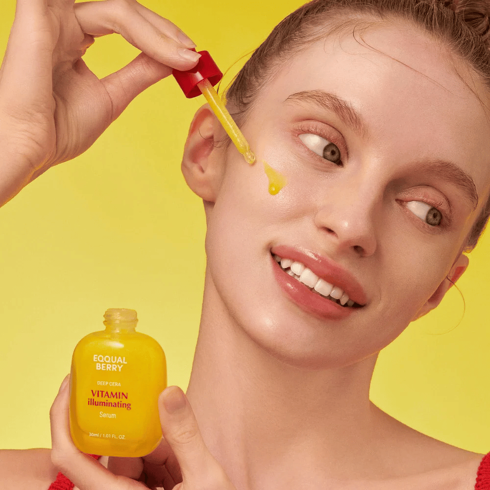 Hymyilevä nainen levittää Equal Berry Vitamin Illuminating Serum pipetillä. Raikas ja säteilevä iho eloisalla keltaisella taustalla, joka vastaa seerumin väriä.