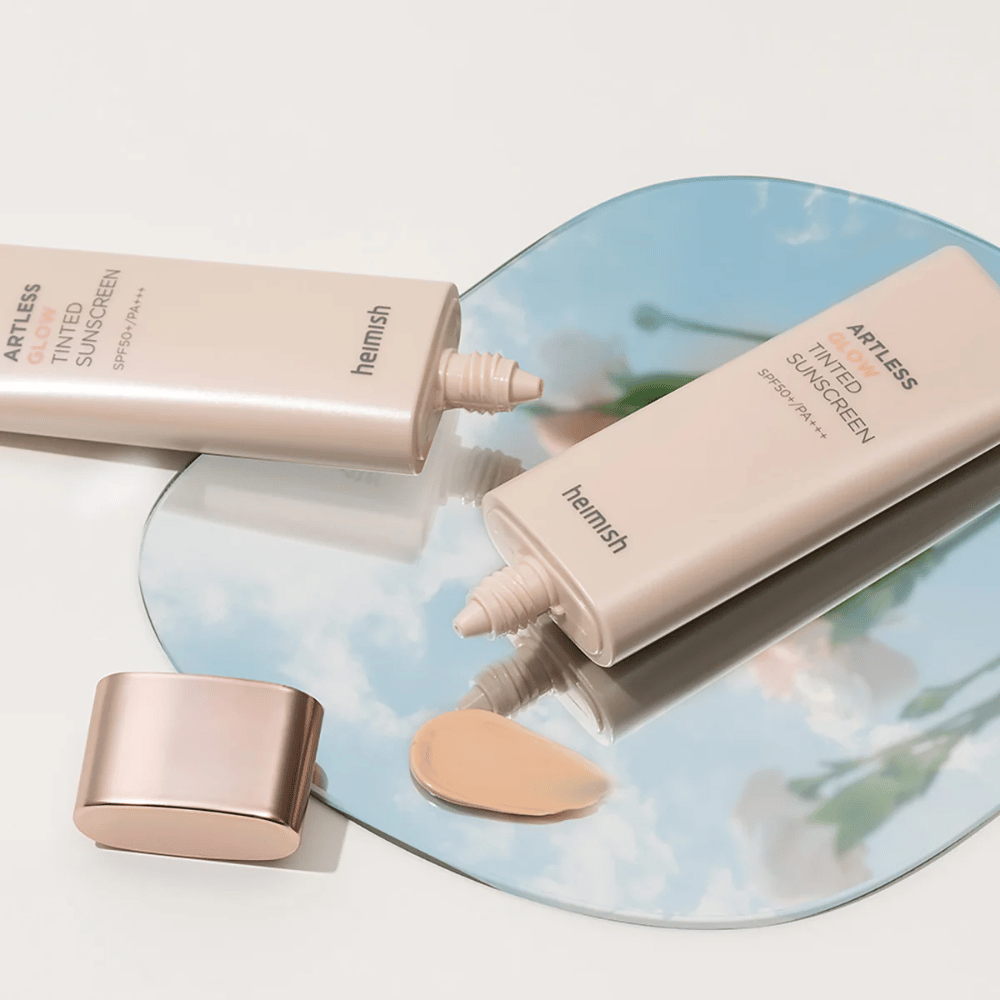 Pullo heimish Artless Glow Tinted Sunscreen SPF50+ PA+++ 40 ml ja pullo concealer peilin päällä, joka näyttää erilaisia ihonsävyjä.