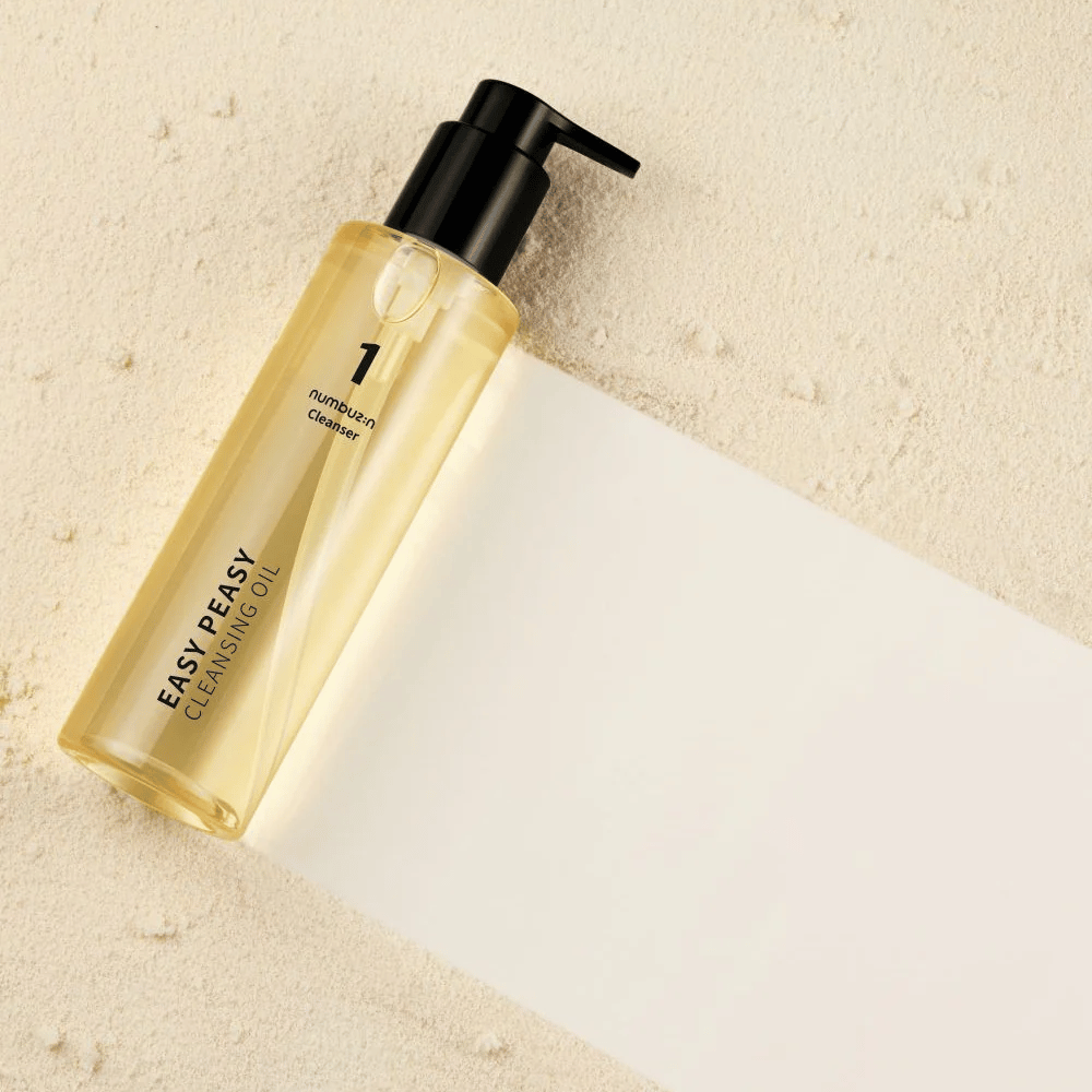 Numbuzin No.1 Easy Peasy Cleansing Oil makaa hiekanvärisellä pinnalla varjon kanssa.
