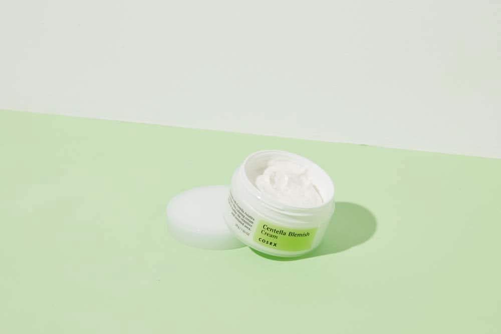 Purkillinen COSRX Centella Blemish Cream 30ml, joka on vihreällä pinnalla.