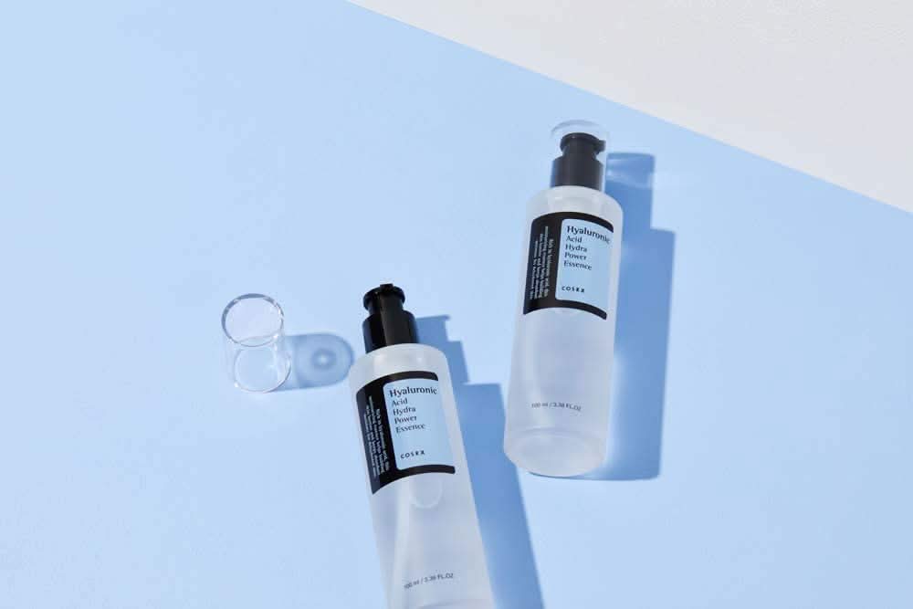 COSRX:n Hyaluronic Acid Hydra Power Essence 100ml tarjoaa kosteuttavia etuja sinisellä pinnalla.
