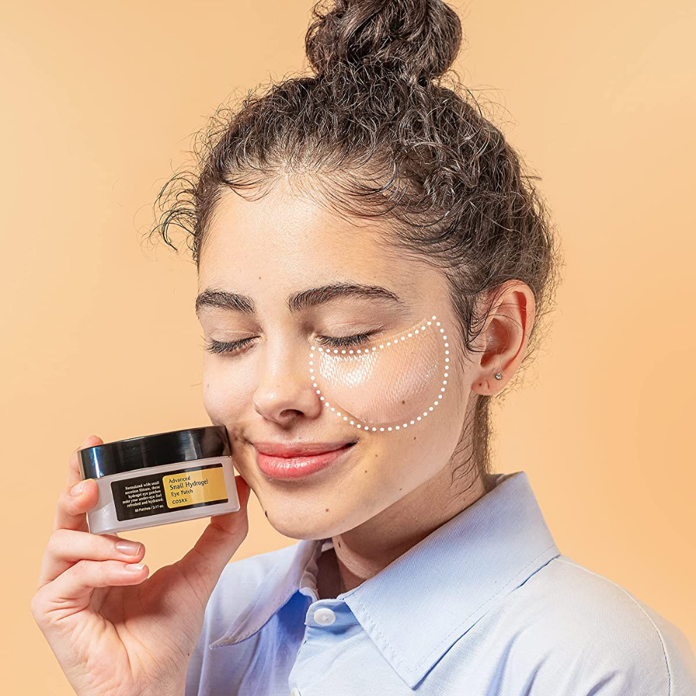 Nainen, joka pitää kädessään purkkia COSRX Advanced Snail Hydrogel Eye Patch 60 kpl kasvovoidetta.