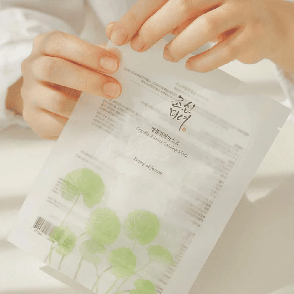 Henkilö, joka pitää ylhäällä paperiarkkia, jossa on Beauty of Joseon Centella Asiatica Calming Mask 1 kpl.