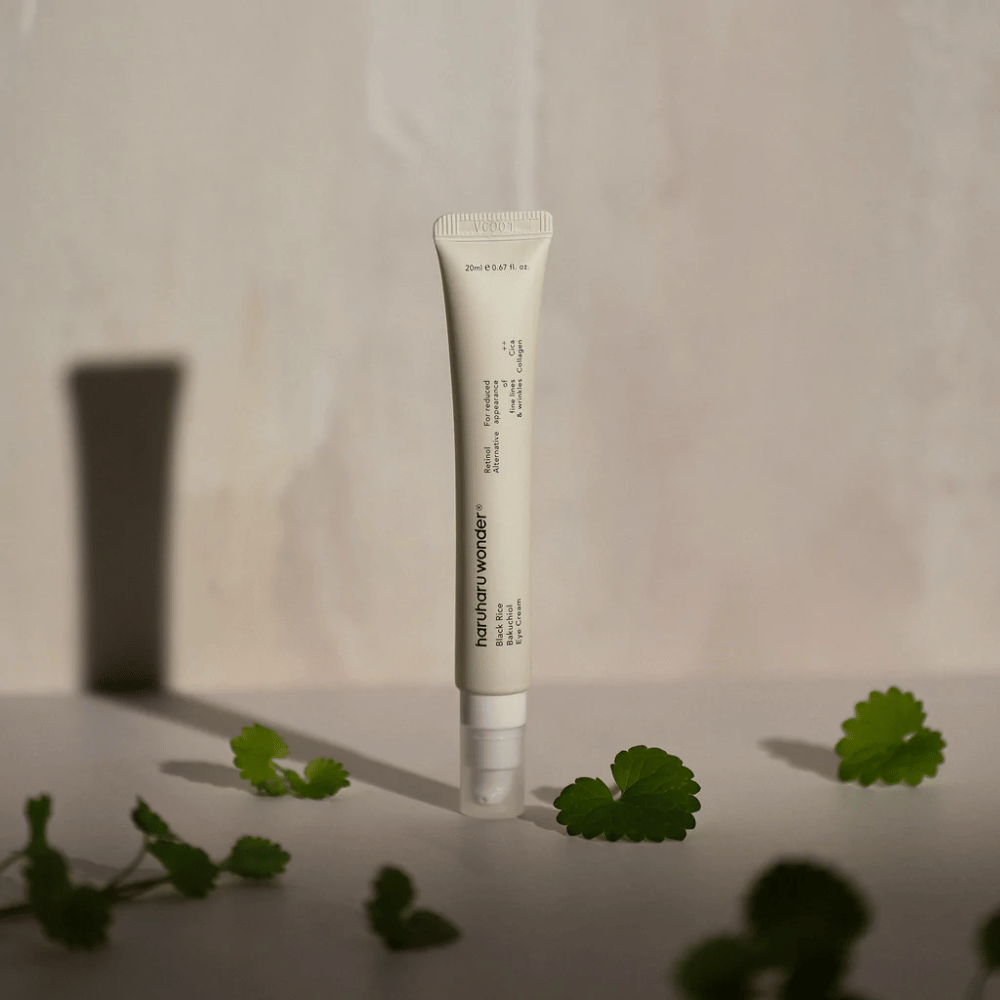 Putkilo Haruharu Wonder Black Rice Bakuchiol Eye Cream 20 ml vihreiden lehtien ympäröimänä, keskittyen ryppyjen ja hienojen juonteiden näkyvyyteen.