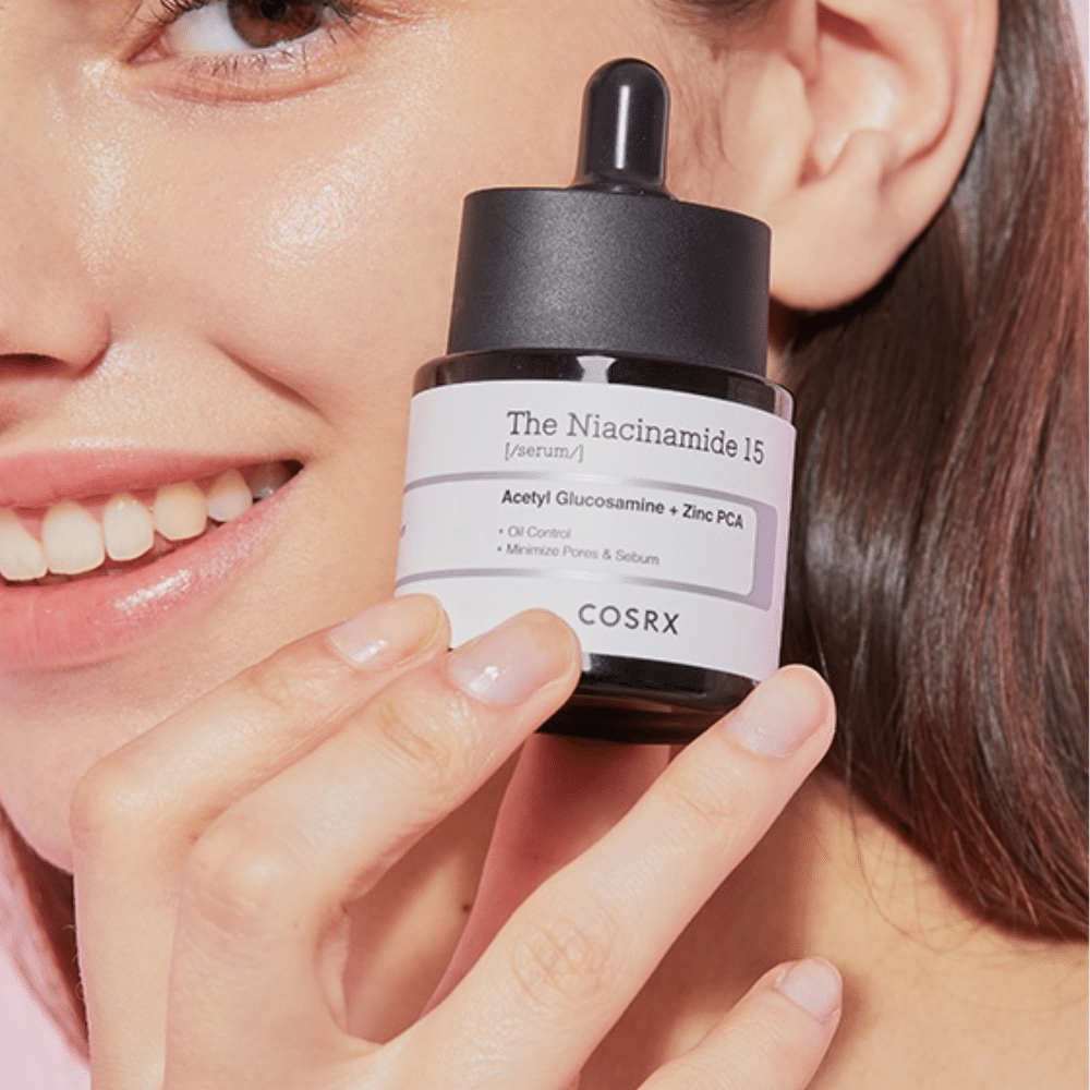 Nainen pitää kädessään pulloa COSRX Niacinamide 15 Serum 20 ml niasiinamidia ja talintuotantoa varten.